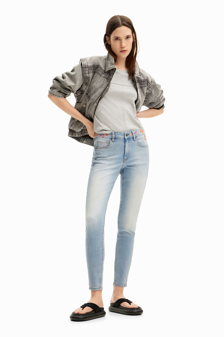 Long denim pants with flowers on the waist.